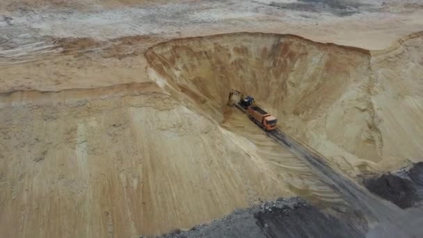 Excavadora y camión volquete. Vista aérea de la carga de arena en un camión. Una maquinaria pesada excavadora y camión están trabajando en la cantera de arena . — Vídeo de stock
