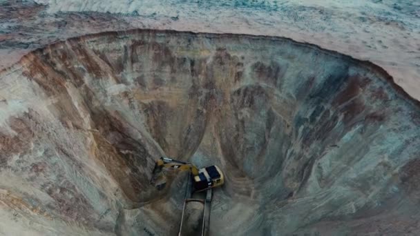 발굴자가 하 일러 트럭에 흙을 싣고, 공중에서 가장 높은 곳에 있는 영상입니다. 거대 한 기계 - 굴착기와 트럭 이 모래 채석장에서 일하고 있다. — 비디오