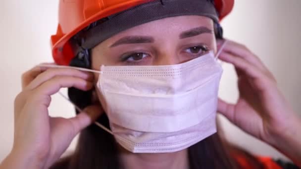 Mujer trabajadora de la construcción en overoles quitando máscara médica de la cara sobre fondo blanco . — Vídeo de stock