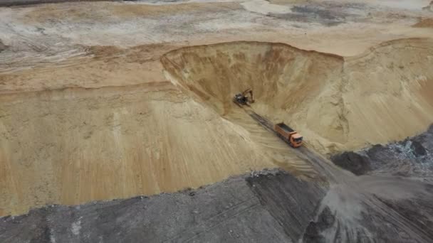 Excavadora y camión volquete. Vista aérea de la carga de arena en un camión. Una maquinaria pesada excavadora y camión están trabajando en la cantera de arena . — Vídeos de Stock