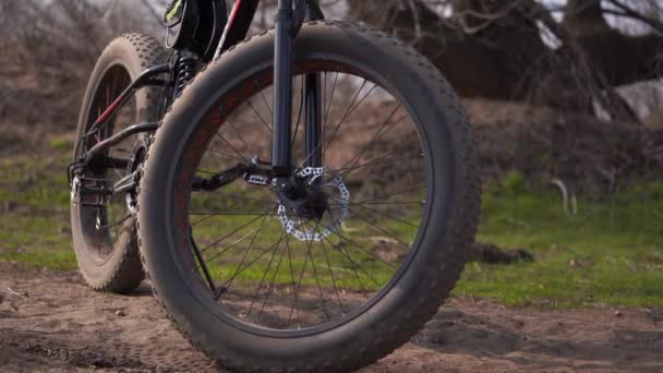 Close-up de bicicleta com rodas grandes no campo. Mountain bike fica no chão em tempo ensolarado . — Vídeo de Stock