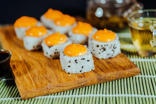 Вкусные роллы с острым соусом на деревянной доске. Крупный план вкусных суши-роллов . — стоковое фото