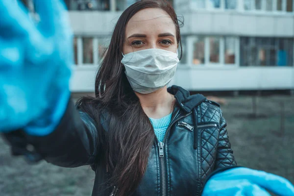 Портрет молодой женщины в медицинской маске на лице, стоящей на улице. Взрослая женщина закрыла лицо маской, чтобы защитить себя от болезней. — стоковое фото