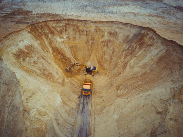 발굴자와 만두 트럭. 트럭에 모래를 실어 나르는걸 공중에서 본 거야. 거대 한 기계 - 굴착기와 트럭 이 모래 채석장에서 일하고 있다. — 스톡 사진