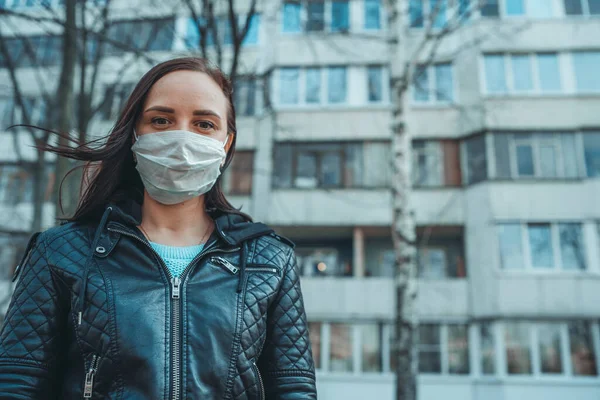 Portret młodej kobiety w masce medycznej na twarzy stojącej na ulicy. Dorosła samica przykryła twarz maską, by chronić się przed chorobami.. — Zdjęcie stockowe