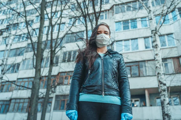 Портрет молодой женщины в медицинской маске на лице, стоящей на улице. Взрослая женщина закрыла лицо маской, чтобы защитить себя от болезней. — стоковое фото