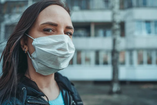 Portret młodej kobiety w masce medycznej na twarzy stojącej na ulicy. Dorosła samica przykryła twarz maską, by chronić się przed chorobami.. — Zdjęcie stockowe