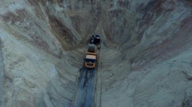 Kazıcı, toprağı nakliye kamyonuna yüklüyor. Ağır bir makine, kazıcı ve kamyon kum ocağında çalışıyor..