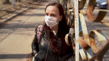 Sokakta duran tıbbi maske takmış genç bir kadının portresi. Yetişkin kadın kendini hastalıklardan korumak için yüzünü maskeyle örttü..