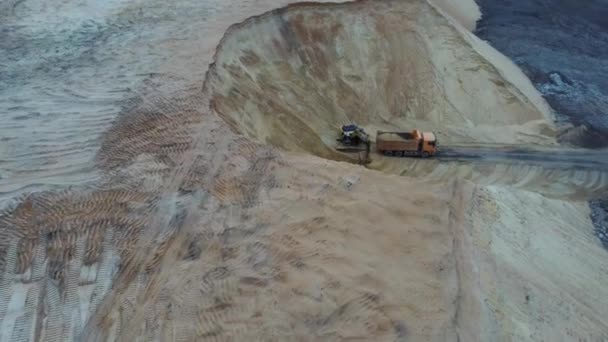 Excavator and dumper truck. Aerial view of loading sand into a truck. A heavy machinery - excavator and truck are working in the sand quarry. — Stock Video