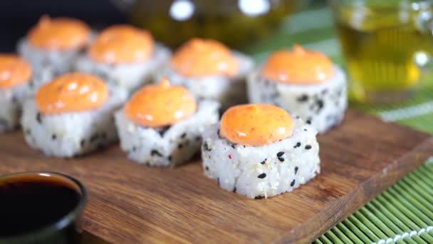 Deliciosos rollos con salsa picante sobre tabla de madera. Primer plano de sabrosos rollos de sushi . — Vídeo de stock
