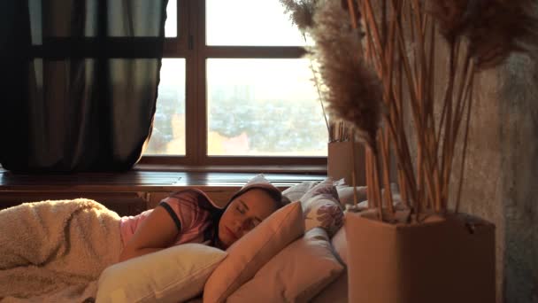 Young woman sleeping on pillows under plaid in bed in early morning. Angry female resenting and covering her head with pillow because of noise that interferes with sleep. — Stock Video