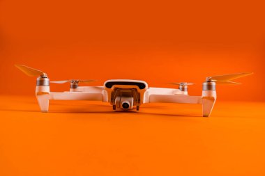 Turuncu arka planda beyaz dronun yakın çekimi. Modern insansız hava aracı, pervaneli..