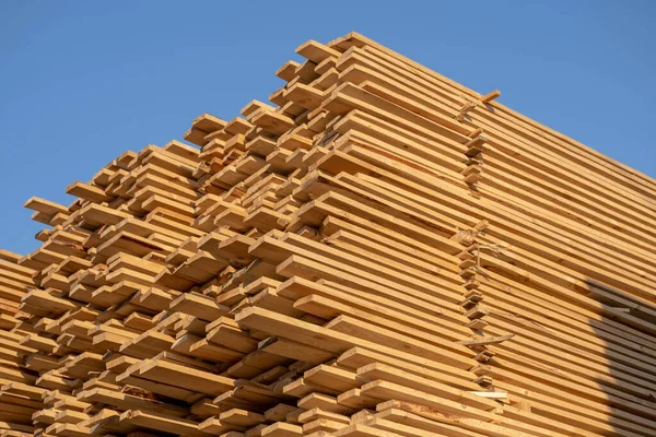 Madera aserrada, madera aserrada industrial, madera aserrada. Madera de pino pila de tableros de madera áspera natural en el sitio de construcción. Materiales de construcción de madera industrial — Foto de Stock