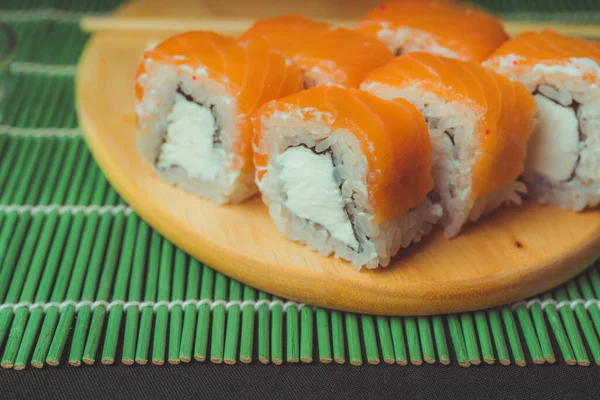 Крупный план вкусных суши-роллов на разделочной доске . — стоковое фото