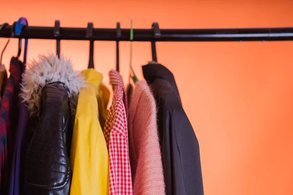 Close up of hangers with clothes on orange background. — Stock Photo, Image