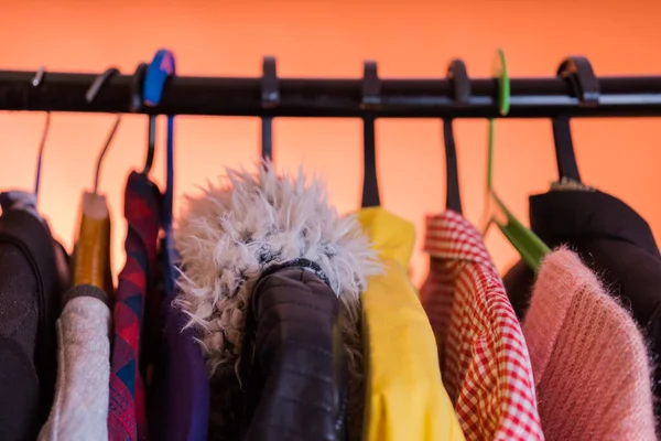 Close up of hangers with clothes on orange background. — Stock Photo, Image