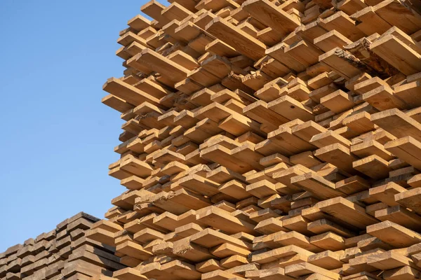 Wooden boards, lumber, industrial wood, timber. Pine wood timber stack of natural rough wooden boards on building site. Industrial timber building materials