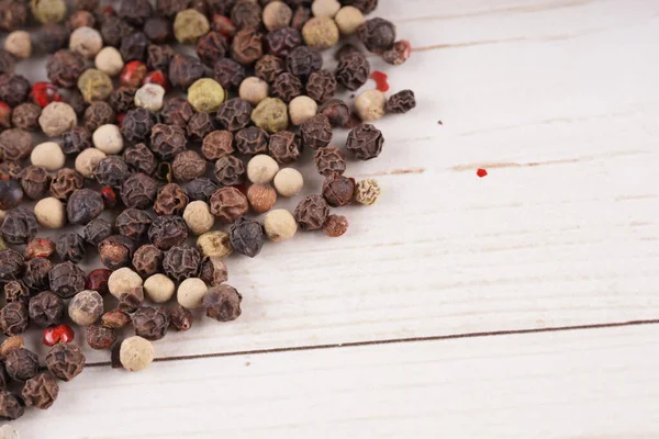 Close-up van specerij op witte houten achtergrond. Stelletje verschillende pepers op tafel met ruimte voor je tekst. — Stockfoto