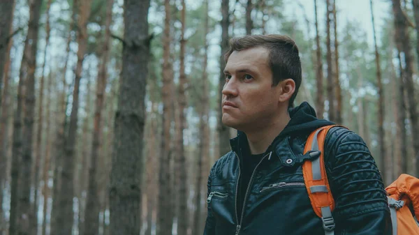 Retrato de un joven viajero en el bosque. Primer plano de hombre adulto en chaqueta de cuero con mochila en el bosque . — Foto de Stock