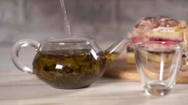Çaydanlıktaki yeşil çayı ve beyaz tahta masadaki fincanı kapat..