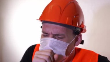 Tulumlu ve maskeli beyaz arka planda öksüren erkek inşaat işçisi. Enfeksiyon tehdidi kavramı.