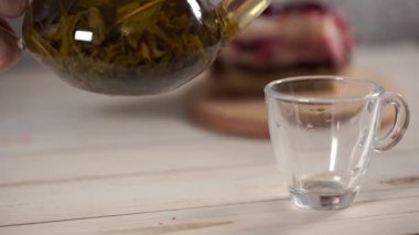 Çaydanlıktaki yeşil çayı ve beyaz tahta masadaki fincanı kapat..