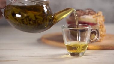 Çaydanlıktaki yeşil çayı ve beyaz tahta masadaki fincanı kapat..