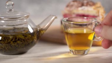 Çaydanlıktaki yeşil çayı ve beyaz tahta masadaki fincanı kapat..