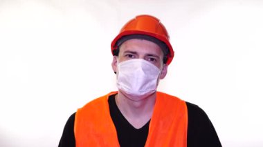 Beyaz arka planda yüzünde tıbbi maske takan genç bir adamın portresi. Yetişkin erkek, kendini hastalıklardan korumak için maske takıyor. Koronavirüs salgını veya hastalıklar kavramı.