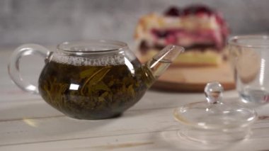 Çaydanlıktaki yeşil çayı ve beyaz tahta masadaki fincanı kapat..