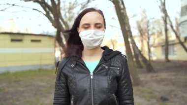 Sokakta duran tıbbi maske takmış genç bir kadının portresi. Yetişkin kadın kendini hastalıklardan korumak için yüzünü maskeyle örttü..
