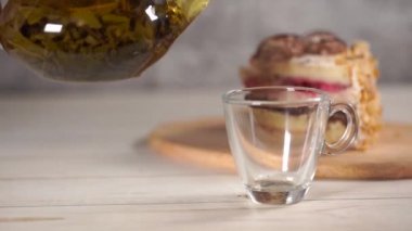Çaydanlıktaki yeşil çayı ve beyaz tahta masadaki fincanı kapat..