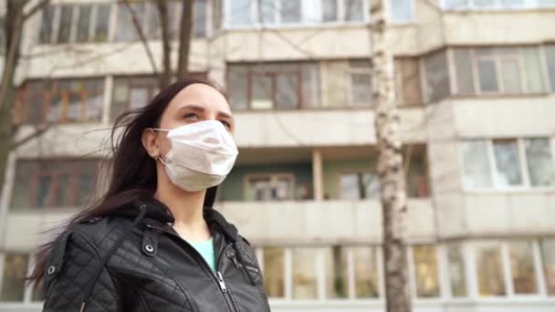 Porträtt av en ung kvinna med medicinsk mask i ansiktet stående på gatan. Vuxen kvinna täckt hennes ansikte med mask för att skydda dig från sjukdomar. — Stockvideo