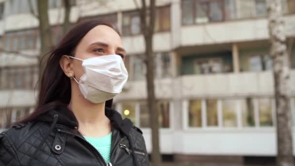 Porträtt av en ung kvinna med medicinsk mask i ansiktet stående på gatan. Vuxen kvinna täckt hennes ansikte med mask för att skydda dig från sjukdomar. — Stockvideo