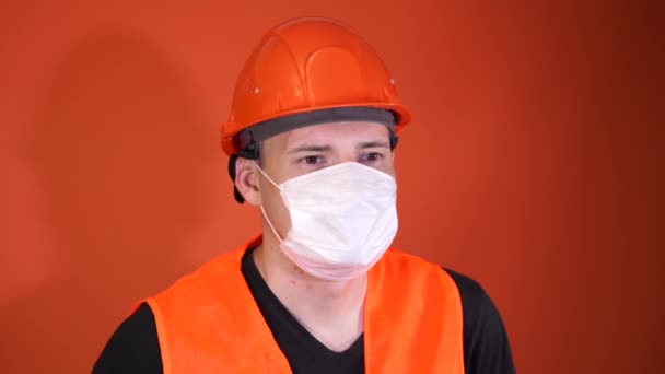 Ritratto di giovane in maschera medica sul viso su sfondo arancione. Maschio adulto coperto viso con maschera per proteggersi dalle malattie. Concetto di epidemia di coronavirus o malattie . — Video Stock
