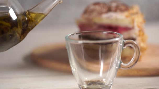 Primer plano de té verde en tetera y taza en mesa de madera blanca . — Vídeo de stock