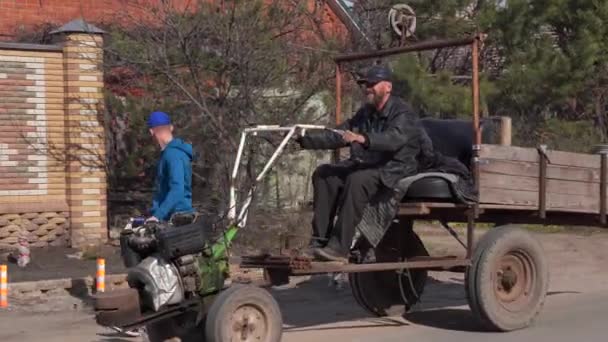 Voronezh, Rusia 31 de marzo de 2020: Hombre mayor cabalgando en transporte hecho a sí mismo en el campo. Maduro macho lleva leche en lata en vehículo hecho a mano. — Vídeos de Stock
