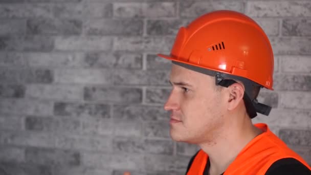 Férfi építőmunkás overálban orvosi maszkot visel az arc háttér szürke téglafal — Stock videók