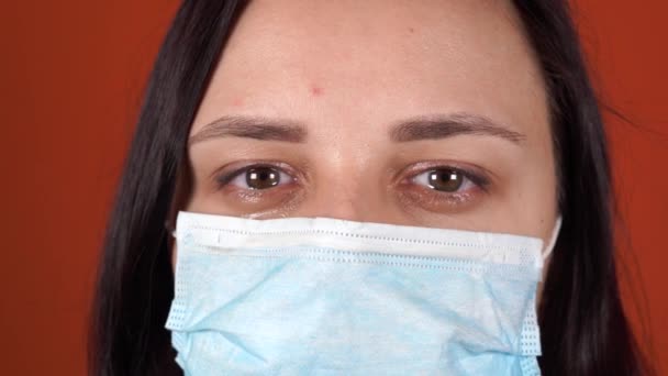 Woman with medical mask on her face. Close-up of womans crying eye. Concept of coronavirus epidemic or diseases. — Stock Video