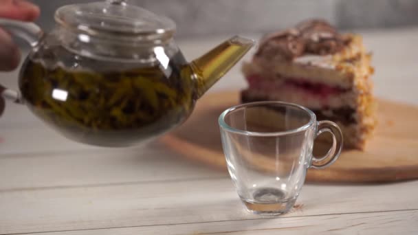 Zblízka zelený čaj v konvice a šálek na bílém dřevěném stole. — Stock video