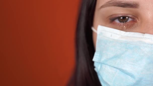 Een vrouw met een medisch masker op zijn gezicht op een oranje achtergrond. De Epidemie van het Coronavirus. — Stockvideo