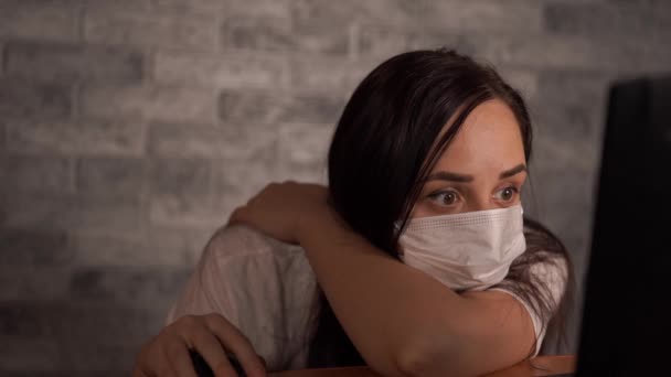 医療用マスクの女性は、ラップトップを使用してインターネットからコロナウイルスに関するニュースを学びます。女性は彼の健康を心配している。コロナウイルスの流行. — ストック動画