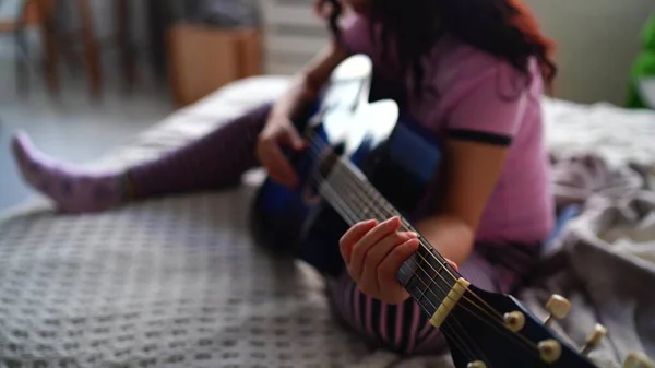 Giovane donna che suona la chitarra in camera da letto. Giovane donna che suona la chitarra nel suo letto. Le piace il suo tempo libero. Bella ragazza suonare la chitarra in una camera da letto accogliente — Foto Stock