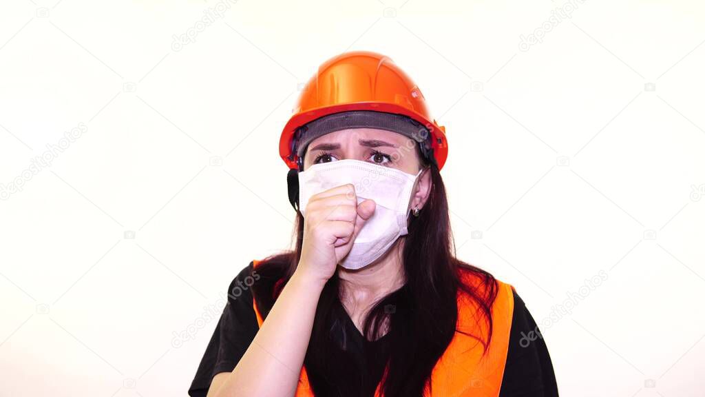 Female construction worker in overalls and medical mask coughing on white background. Concept of threat of infection.