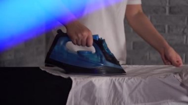 Ütü masasında giysileri ütüleyen kadın, yakın plan.