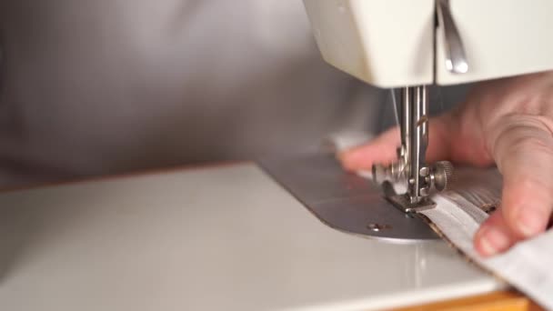 Закрыть швейную машинку с женскими руками на столе. Женщина сшивает занавески, используя швейную машинку . — стоковое видео