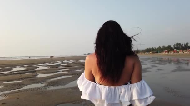 Een vrouw die met zonsondergang op het strand loopt. Concept zomer op vakantie. — Stockvideo