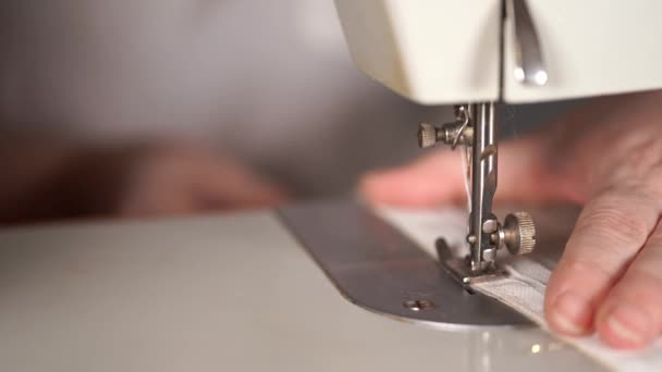 Закрыть швейную машинку с женскими руками на столе. Женщина сшивает занавески, используя швейную машинку . — стоковое видео