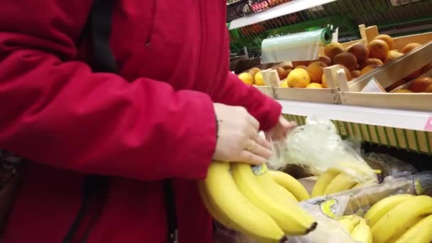 Donna che sceglie banane in serbo. Primo piano delle mani delle donne alla ricerca di buoni frutti sul bancone del negozio . — Video Stock